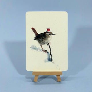 Aquarell-Illustration eines Zaunkönigs im Schnee mit Ast und Weihnachtskrone.