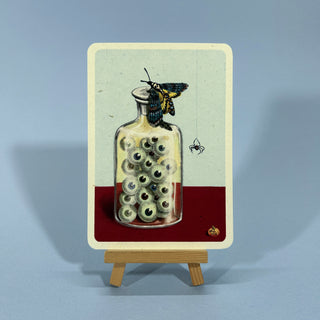 Augäpfel in einem Apothekerglas. Auf dem Deckel sitzt eine Totenkopf-Motte.
Daneben hängt eine pinne am Faden.