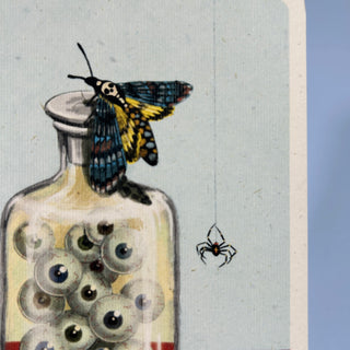 Augäpfel in einem Apothekerglas. Auf dem Deckel sitzt eine Totenkopf-Motte.
Daneben hängt eine pinne am Faden.