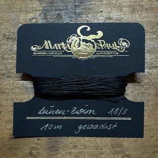 gewachster schwarzer Zwirn auf Karte gewickelt