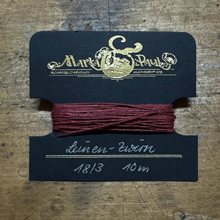 ungewachster weinroter Zwirn auf Karte gewickelt